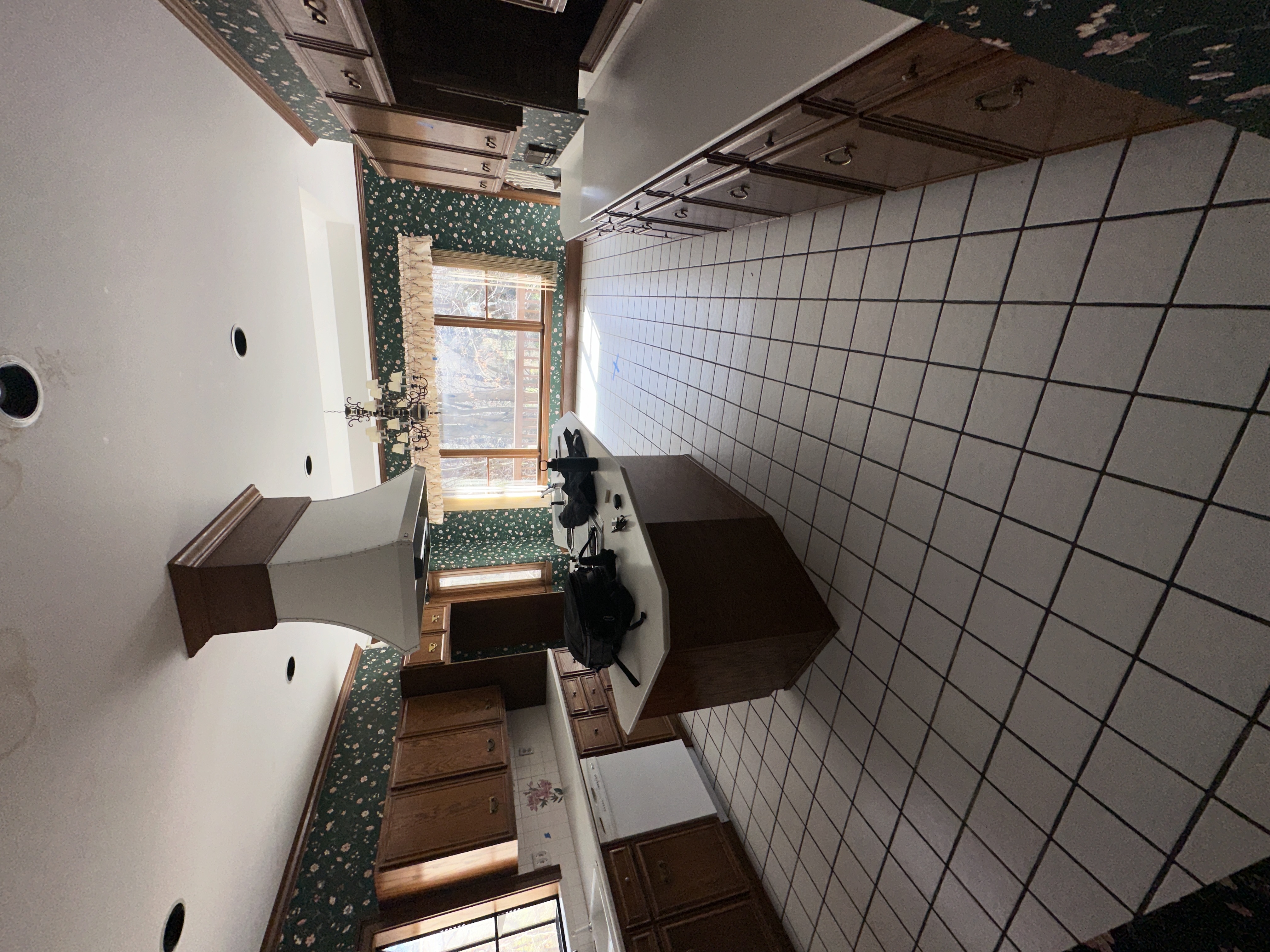 Kitchen before — dated tile and wallpaper