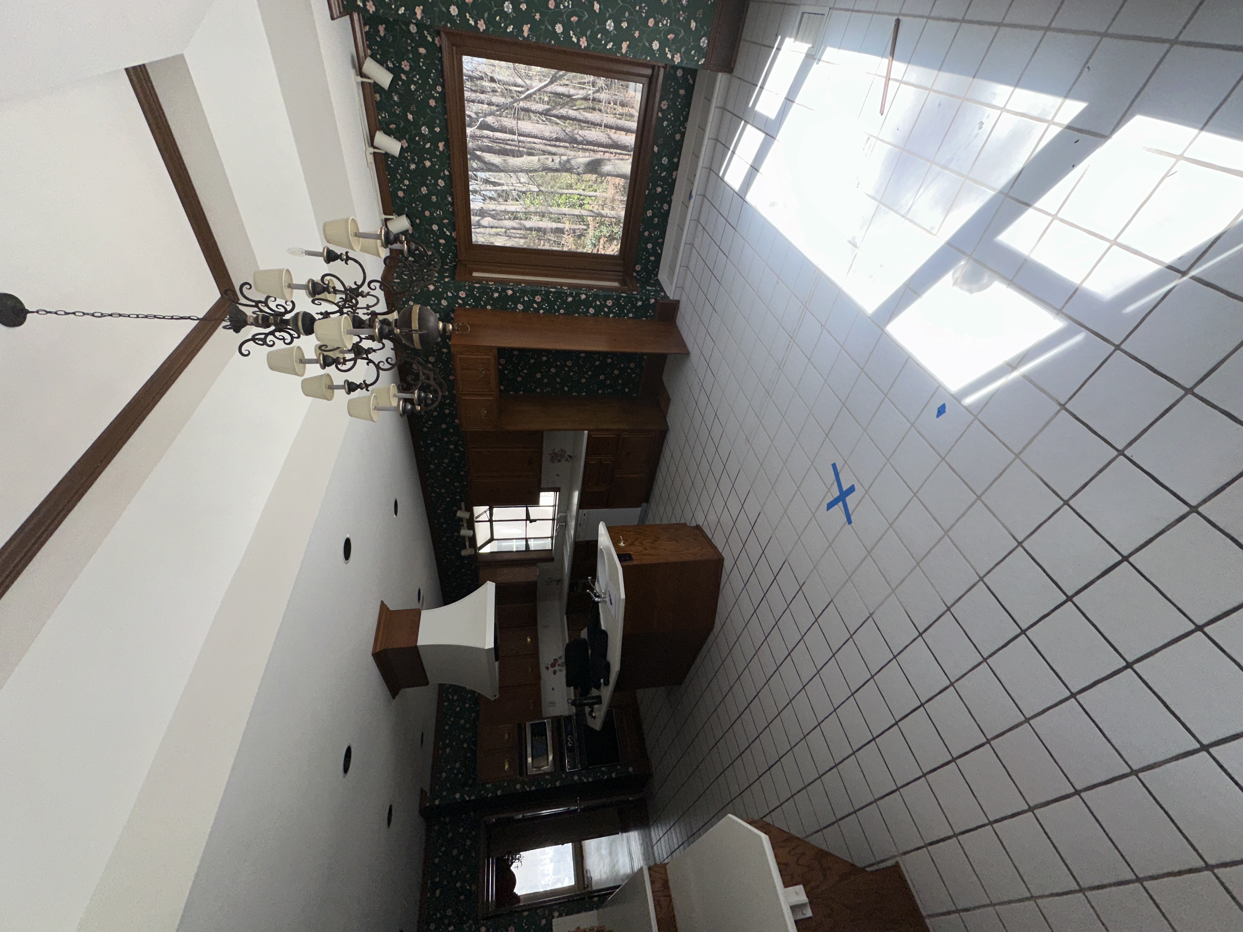 Kitchen before — green wallpaper, white tile, skylight
