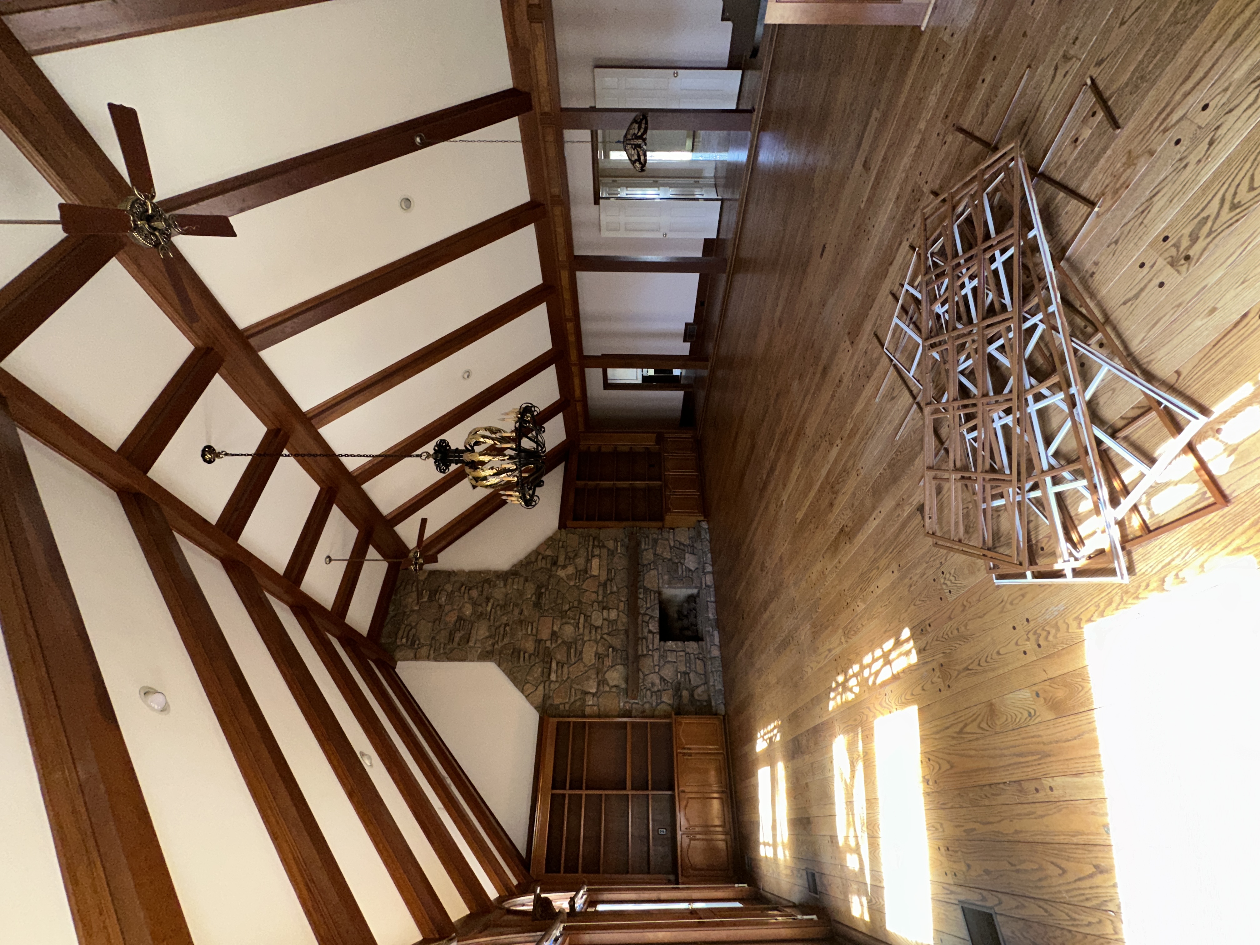 Great room before — vaulted wood beams, stone fireplace, wood paneling