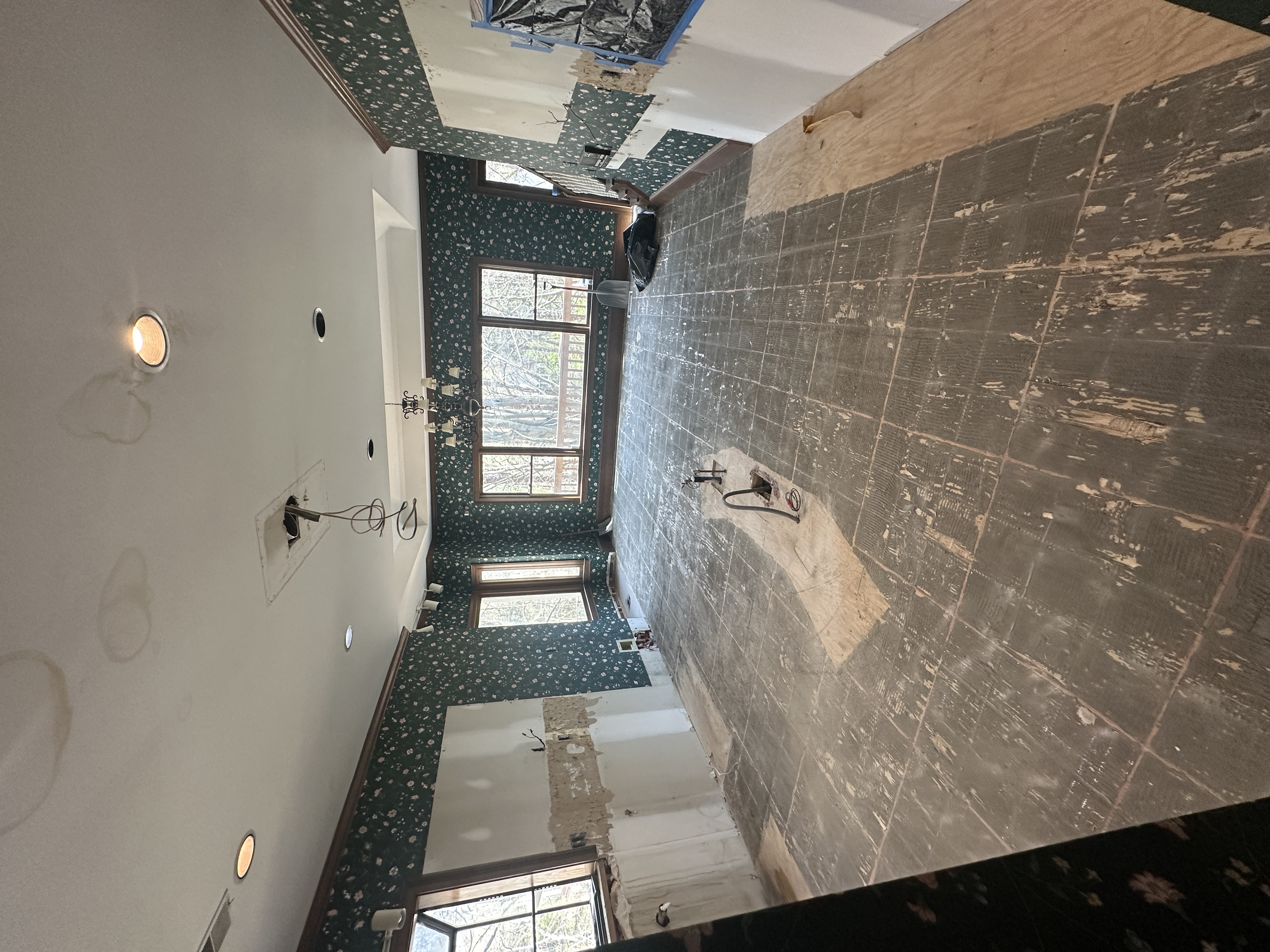 Bathroom before — green wallpaper, tile being demolished
