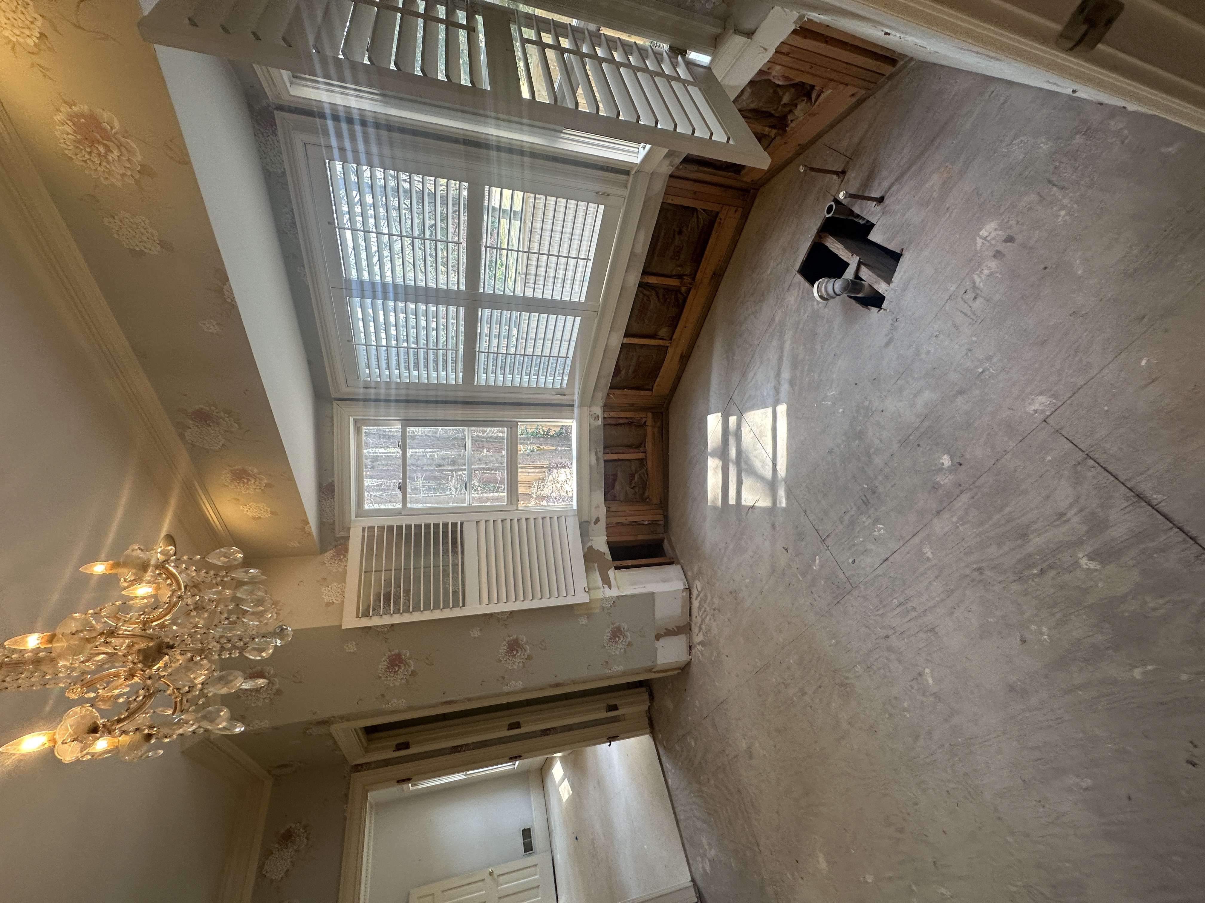Room before — chandelier, wallpaper, exposed framing