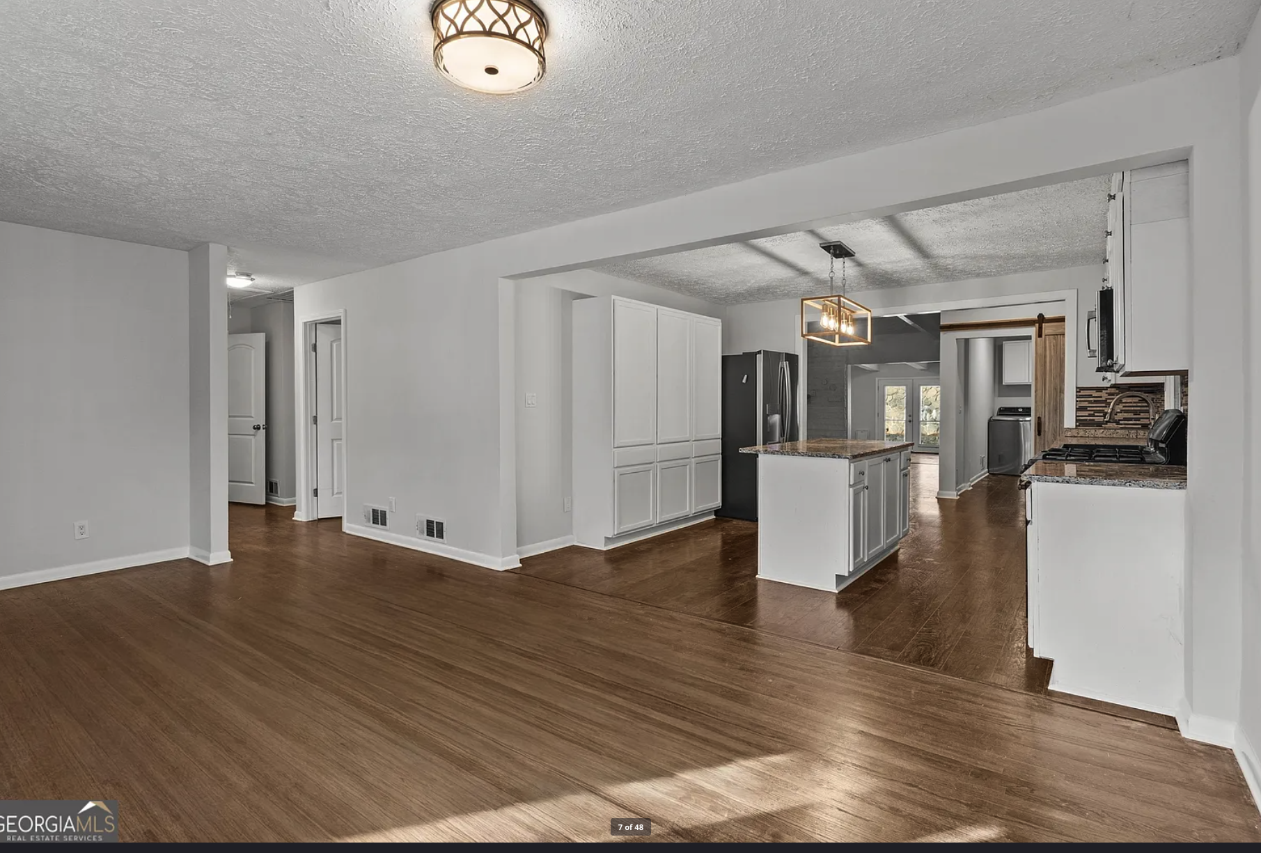 Open plan kitchen — white shaker cabinets, island, hardwood
