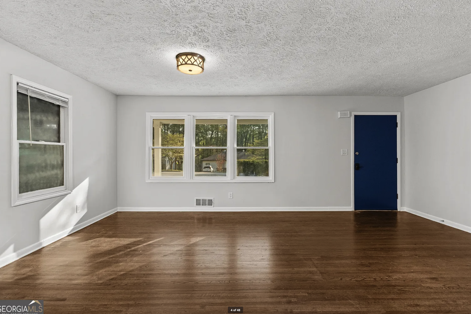 Living room after — hardwood floors, white walls, blue door