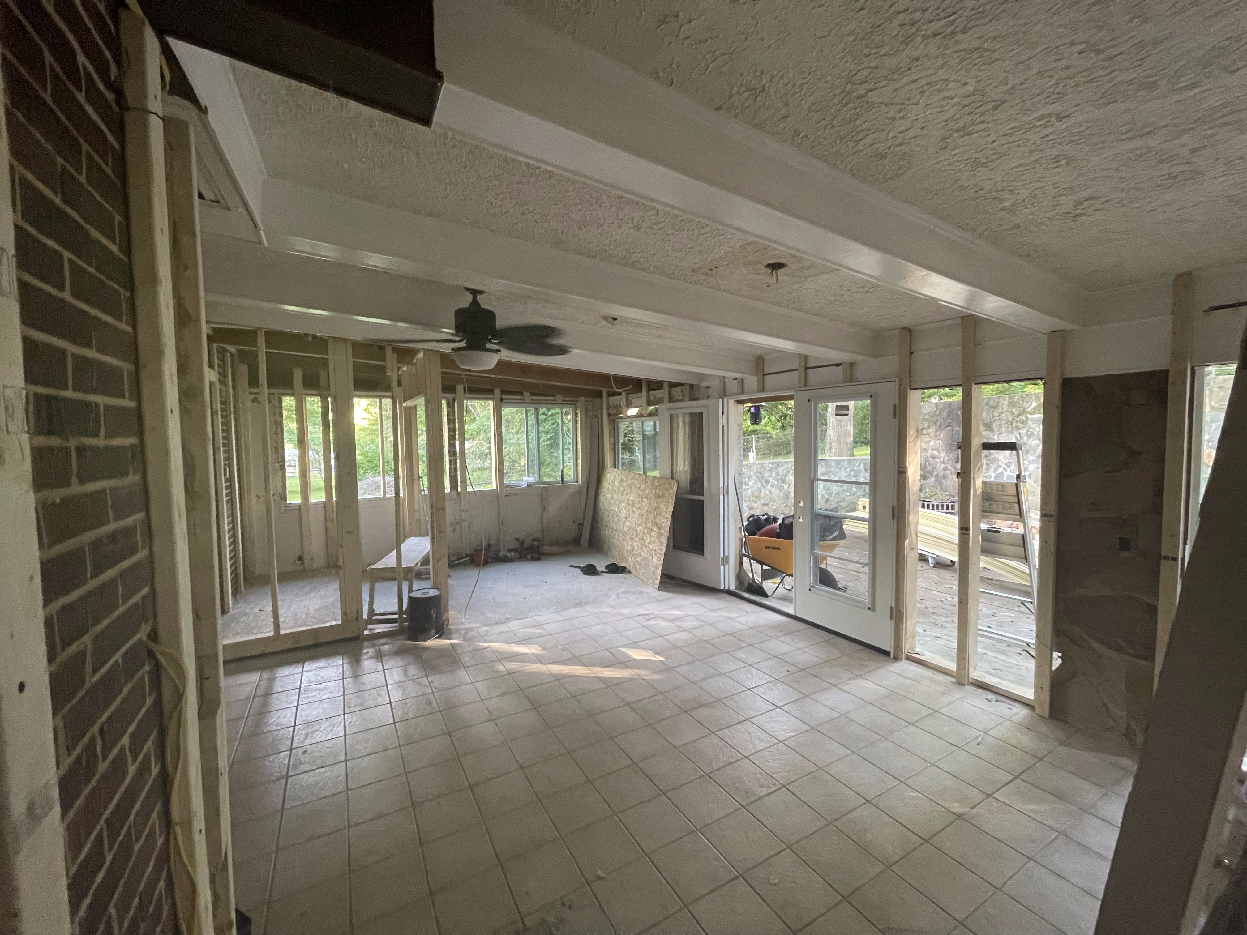 Great room before — gutted, exposed beams, brick wall