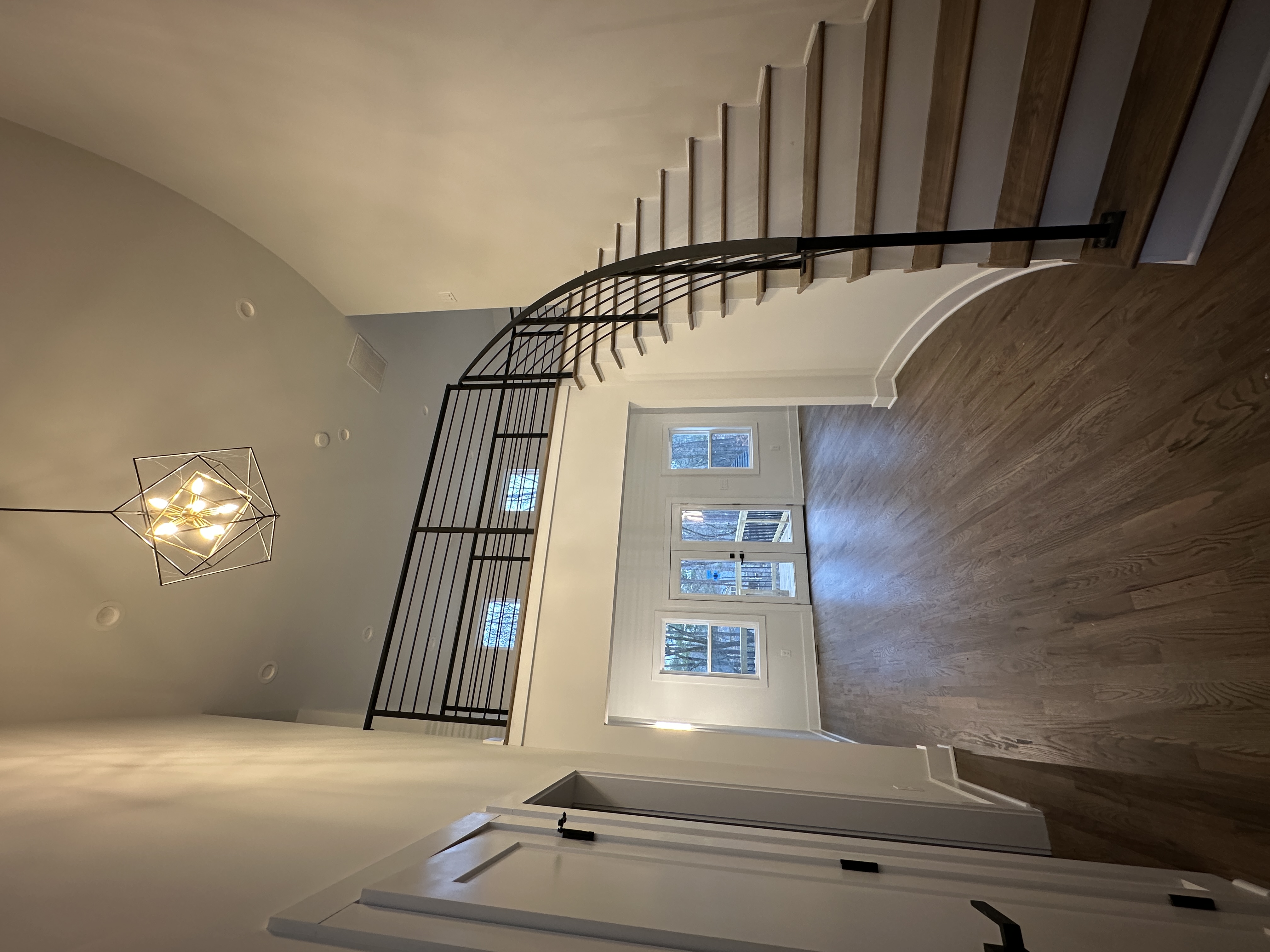 Rebuilt foyer with curved staircase and geometric chandelier